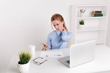 Office woman sitting infront of the computer at her workplace and feeling neckache. Sad worker feeling upset and tired