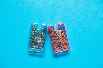 Safety pins  in blue and pink plastic boxes on blue background