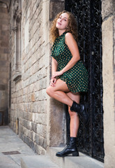 Young sexy woman in dress standing near the stone wall  and showing legs