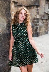 Young sexy woman in dress standing near the stone wall  in historical center