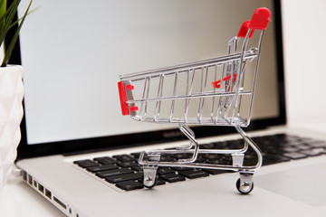 paper boxes in a shopping cart on a laptop keyboard. Concepts about online shopping that consumers...