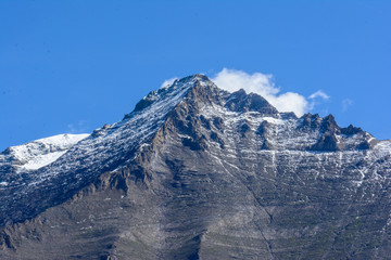 Berggipfel vor  blauen Himmel mit Wolken mit Schnee