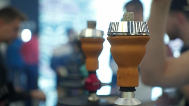 People choosing hookah. Smoking tobacco at exhibition. Shisha bowl at event