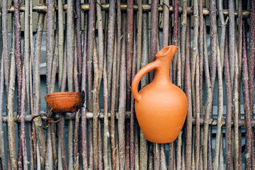 Clay jugs on a decorative fence made of tree branches.