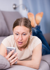 Woman looking at phone on sofa