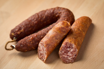 Luftgetrockneter Mettwurst Ring und frische Bierbeißer, zwei Salami Sorten aus Schweinefleisch auf Holz Brett 