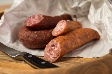 Ringwurst Salami und Bierbeißer Wurst in Wachspapier mit Messer auf Vesper Holzbrett