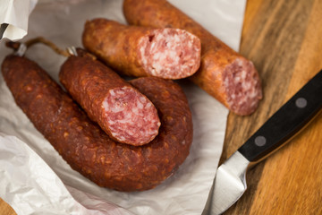 Ringwurst Salami und Bierbeißer Wurst in Wachspapier mit Messer auf Vesper Holzbrett