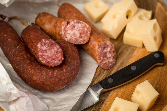 Ringwurst Salami, Bierbei&szlig;er Wurst und Edamer K&auml;se in Wachspapier mit Messer auf Vesper Holzbrett