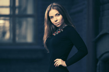 Happy young fashion woman in black dress walking on city street