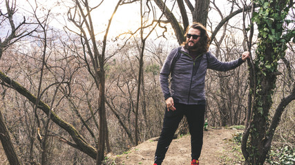 Young guy with long hair and sun glasses hiking in the forest