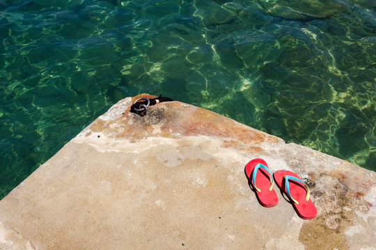 Una chancletas rojas sobre una plata de ba&ntilde;o en una isla de Grecia, sugieren un ba&ntilde;o en el mar
