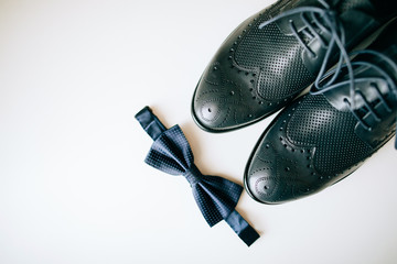 Close up of wedding man accessories, bowtie, leather shoes on white background