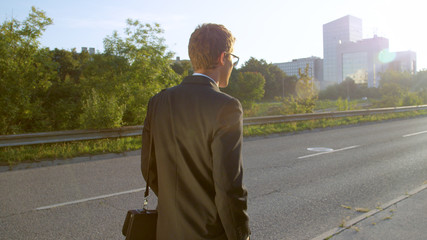 CLOSE UP: Young man in a black suit casually walking to a business meeting.