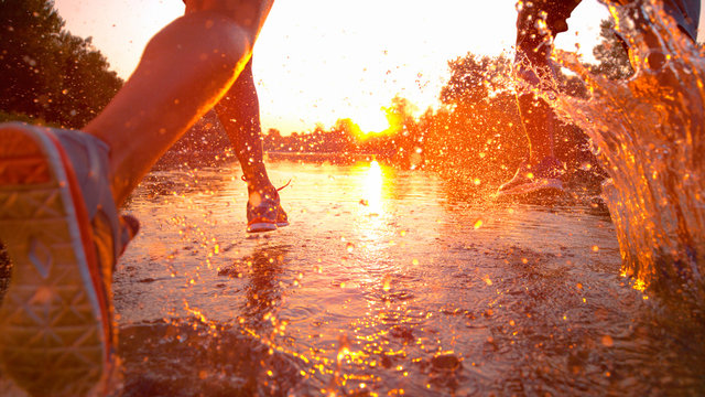 SUN FLARE Unrecognizable man and woman splash the refreshing water while jogging