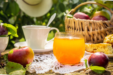 Lunch breakfast on the terrace in the garden. Orange juice, pie, coffee, tea, apples on a wooden...