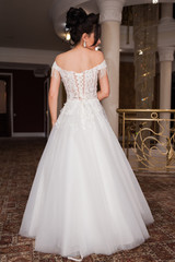 Beauty portrait of bride wearing fashion wedding dress with feathers with luxury delight make-up and hairstyle, studio indoor photo