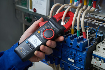 Electrician work concept. Hand with multimeter tester in switchbox - obrazy, fototapety, plakaty