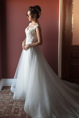 Fototapeta premium Portrait of a beautiful bride woman in elegant white wedding dress. Luxurious apartments. 