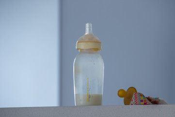 A baby's bottle and a pacifier on a shelf in a suburban home image with copy space in landscape...