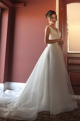 Fototapeta premium Portrait of a beautiful bride woman in elegant white wedding dress. Luxurious apartments. 