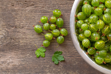 Ripe gooseberry on a rustic wood in the bowl place for text, top view, summer harvest of berries