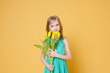 Beautiful funny blonde gives her mother a bouquet of yellow tulips. Holiday, fashion and beauty concept. Selective focus.	