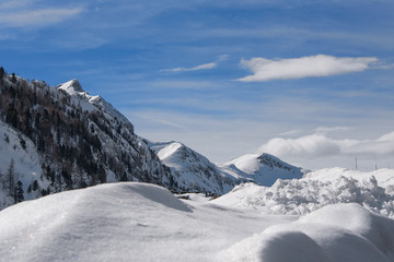 A beautiful winter landscape with snow-covered mountains and blue sky in the background, and with a high snow on the slope in the foreground; sunny day in the european Alps; ski in Obertauern, Austria