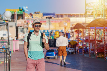 European tourist is eating tasty ice-cream in the amusement park.