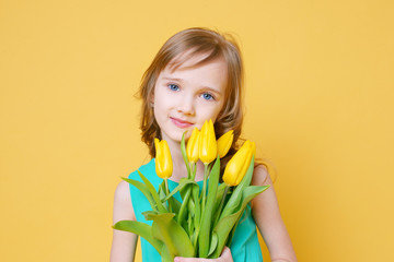 Cute funny blonde gives her mother a bouquet of yellow tulips. Holiday, fashion and beauty concept. Selective focus.	