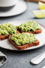 Three sandwiches with rye bread and mashed avocado on a plate. The concept of healthy vegetarian breakfast.