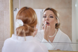 Young girl is coloring her lips in a bath in front of the mirror.