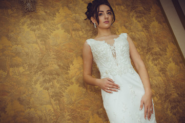 Fototapeta na wymiar Portrait of a beautiful bride woman in elegant white wedding dress. Luxurious apartments. 