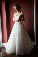 Fototapeta na wymiar Portrait of a beautiful bride woman in elegant white wedding dress. Luxurious apartments. 