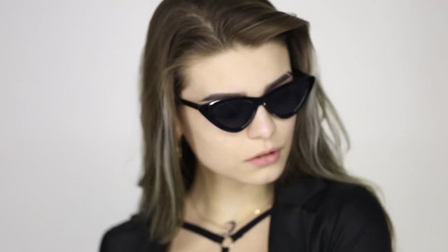 Girl in black lacquered pants and sunglasses on a white background