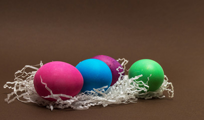 Creative Colorful Easter eggs and craft paper on chocolate background.