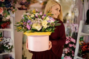 Blond woman holding hat box with flowers