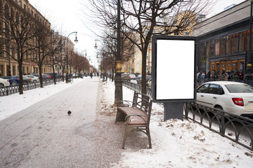 Vertical city billboard with white field MOCKUP. In the city center in the afternoon with snow in the winter. outdoor advertising ad