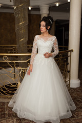 Fototapeta premium Beauty portrait of bride wearing fashion wedding dress with feathers with luxury delight make-up and hairstyle studio indoor photo.