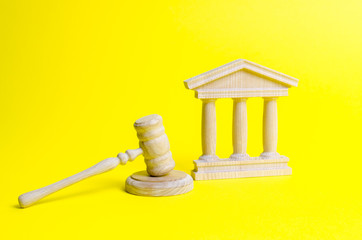 Wooden judge hammer and government building on a yellow background. Court. Concept of the state...