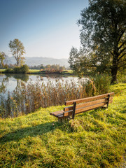Beautiful autumn morning at the Kreutsee in Kiefersfelden with bench in the foreground