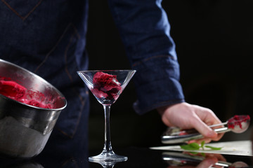 The cook in the restaurant lays out freshly made beetroot ice cream in a tall bowl. Restaurant concept.