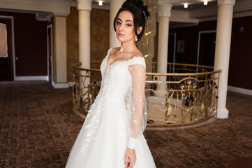 Naklejka premium beautiful bride in chic dress. delicate bride with long hair. girl in lace dress with loop in studio Bride%27s morning in a stylish interior