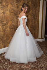Fototapeta premium Beauty portrait of bride wearing fashion wedding dress with feathers with luxury delight make-up and hairstyle studio indoor photo.