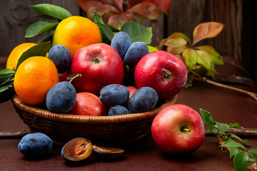 Beautiful red apples, plums, tangerines with green leaves