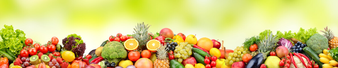Composition variety fresh fruits and vegetables on green background.