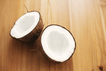 Fototapeta na wymiar Halved coconut on wooden table, flat lay. Hello summer vacation concept. Space for text. Tropical background with coconut. Delicious nut, refreshing drink and oil source, tasty milk