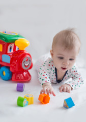 Baby boy grabbing toy with train on white