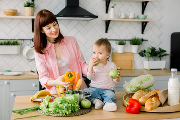 Mother with her daughter in the kitchen preparing healthy food with fresh vegetables, home parenting life style