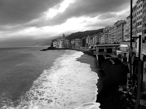 Genova, Italy - 03/08/2019: An amazing caption of small waves and beautiful sunset with an incredible reflection over the sea and some coloured clouds in winter days, and some black and white photos.